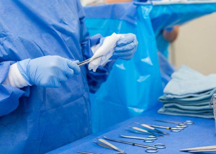 Surgical nurse or technician is sterilizing claps, forceps, and scalpels in hospital operating room. She is cleaning surgical instruments and organizing them before surgical procedure.