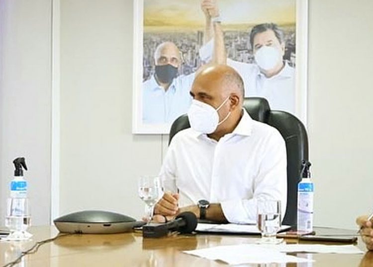 Rogério Cruz em seu gabinete na prefeitura; ao fundo, fotografia sua ao lado de Maguito Vilela | Foto: Jackson Rodrigues