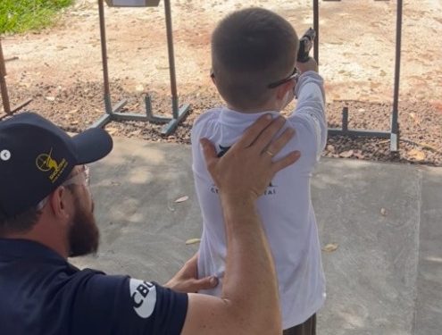 Criança sendo instruída por instrutor do clube de tiro | Foto: redes sociais